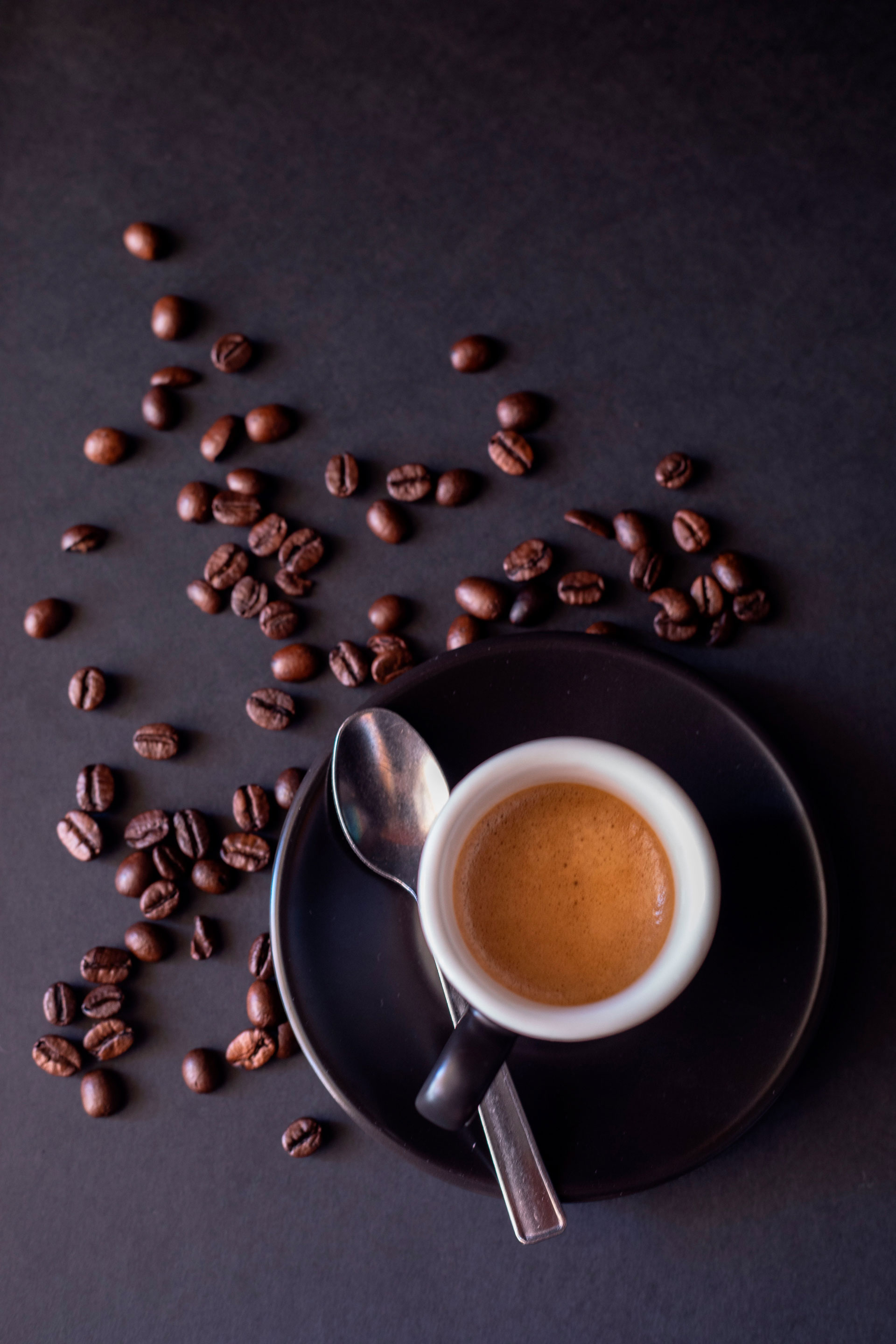 Tazzina nera con caffe e chicchi sparsi